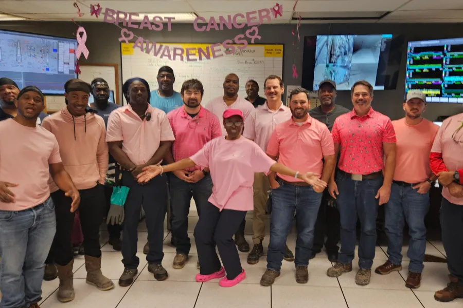 Pulp Mill coworkers wearing pink pose together in the mill control room for Breast Cancer Awareness Month.