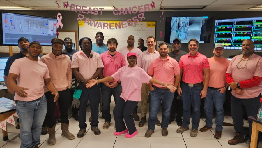 Pulp Mill coworkers wearing pink pose together in the mill control room for Breast Cancer Awareness Month.