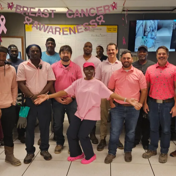 Pulp Mill coworkers wearing pink pose together in the mill control room for Breast Cancer Awareness Month.